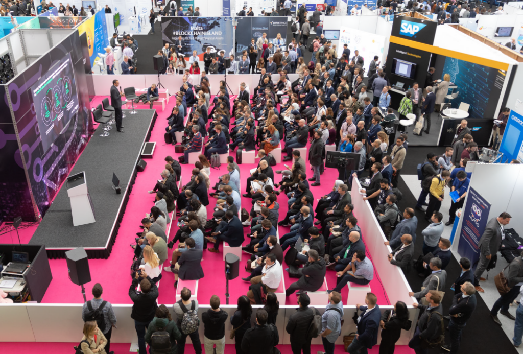 Attendees at the AI Expo North America listen to a presentation amidst the expo's bustling activity